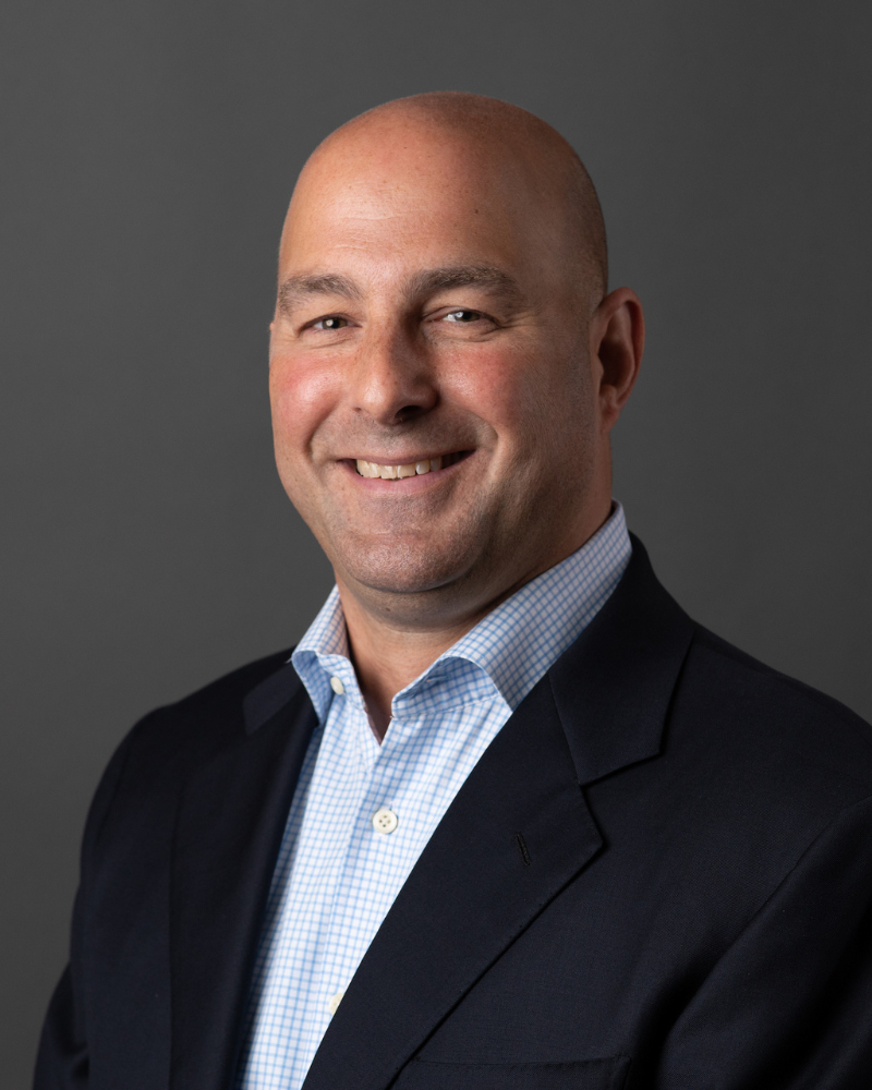 A photo of a man in a blue shirt and black blazer